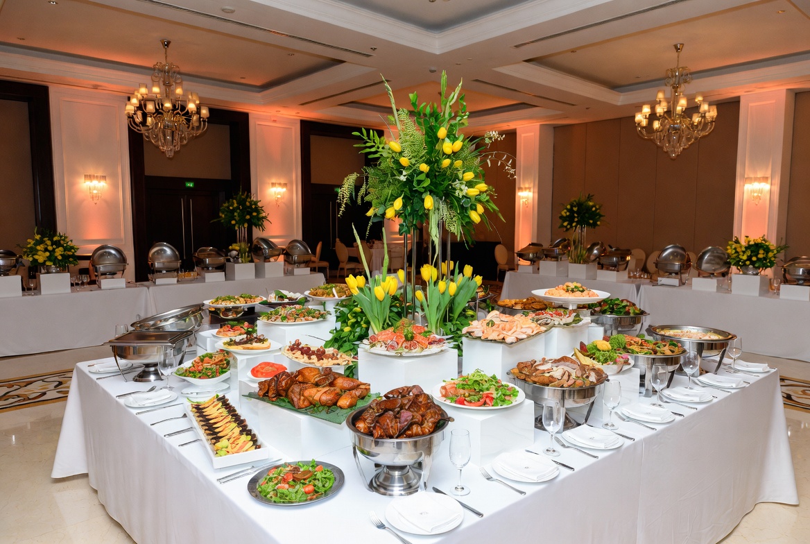 Elegant professional catering buffet with yellow tulip floral arrangements and gourmet food at a luxury event in Oman Convention Centre